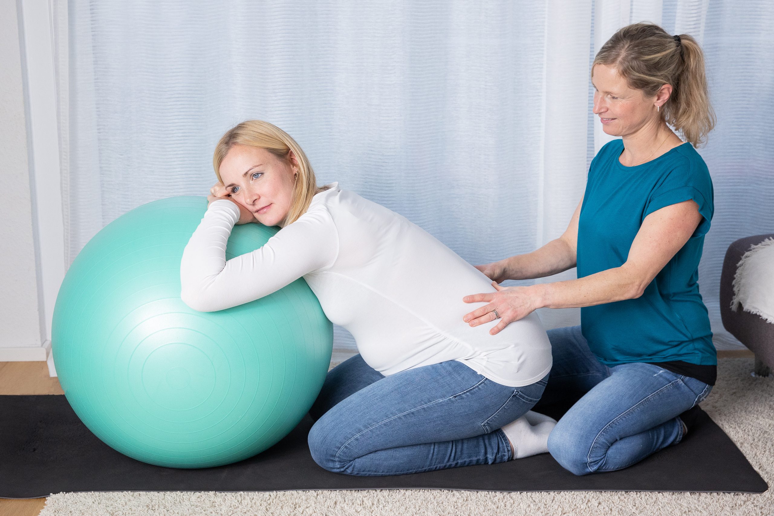 Anne Wenz betreut eine Schwangere, die sich auf einen Gymnastikball stützt